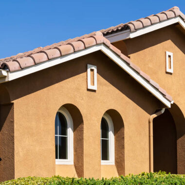 Stucco painting Los Angeles home exterior with fresh brown finish and tile roof