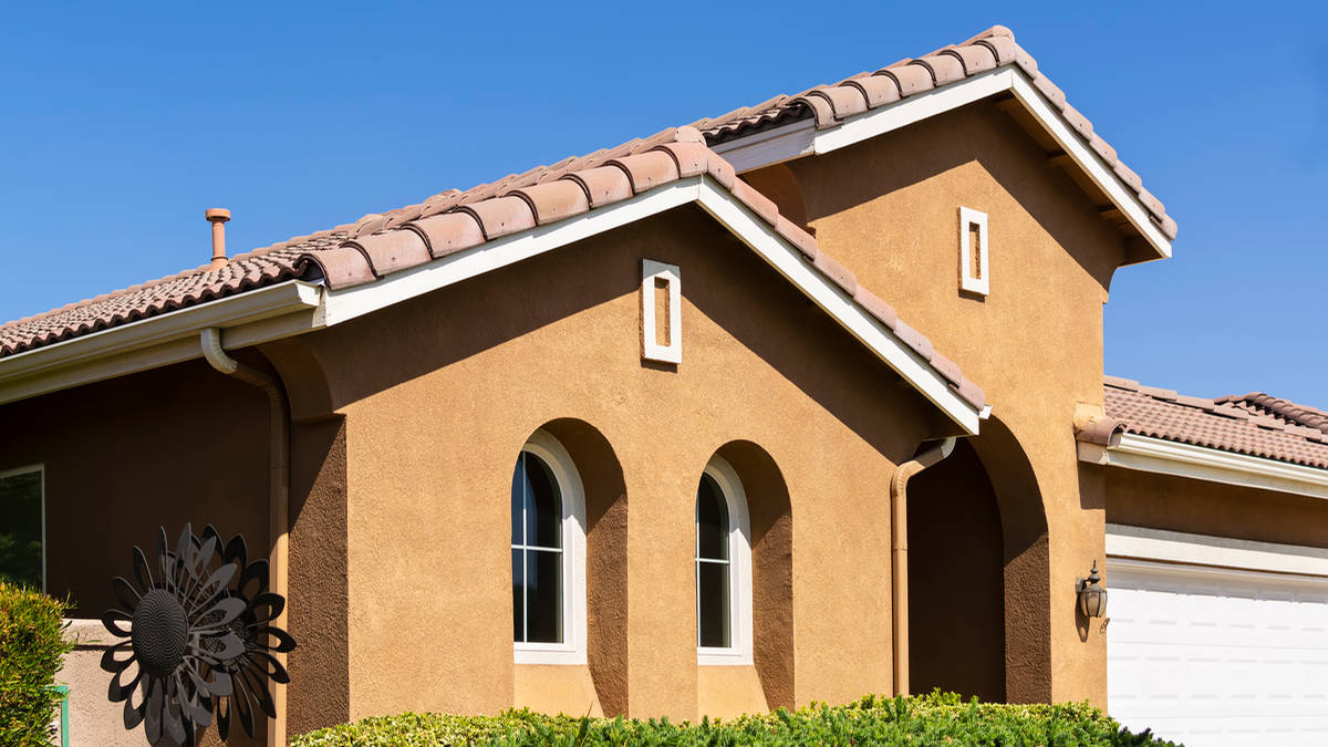 Stucco painting Los Angeles home exterior with fresh brown finish and tile roof