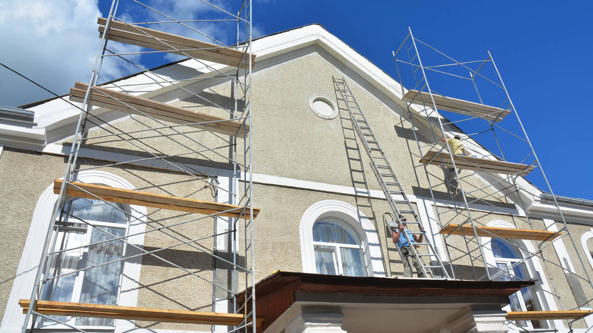 Stucco painting Los Angeles maintenance with scaffolding and repair work on residential exterior