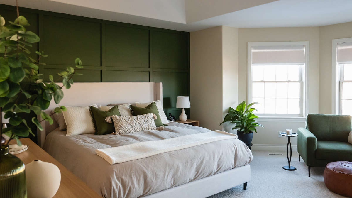 Luxury bedroom interior with deep green accent wall behind upholstered bed, creating a calm and refined statement wall design.