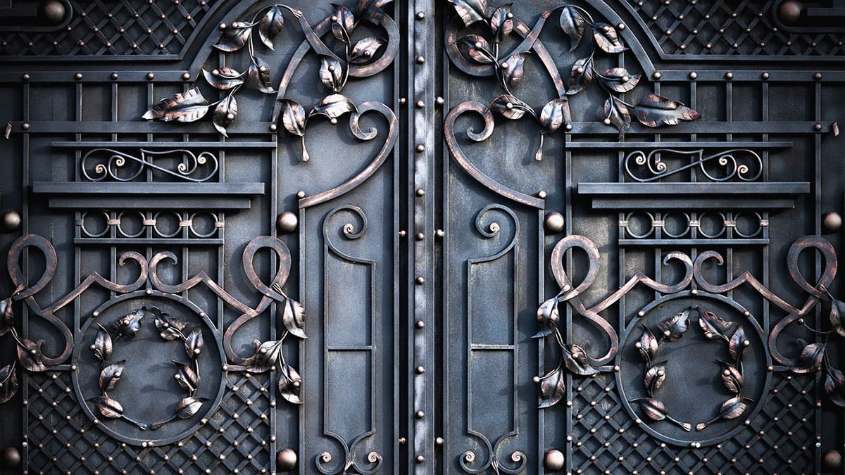 Close-up of an ornate wrought-iron gate with scrollwork, leaf details, and rivets.