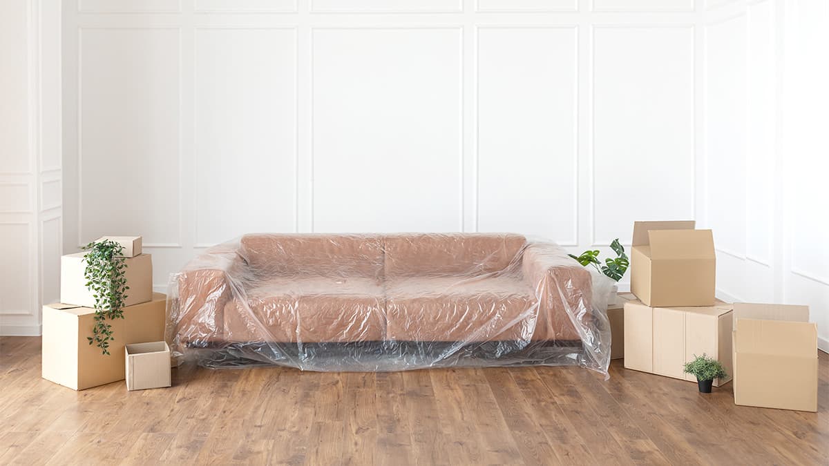 Sofa protected with plastic and household items boxed before a professional paint crew arrives